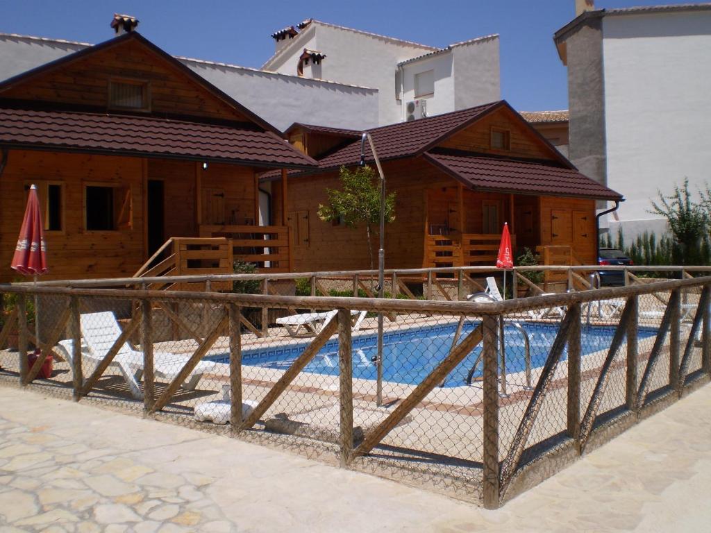 a wooden fence in front of a house with a pool at Cabañas de Madera El Rinconcillo in Arroyo Frio