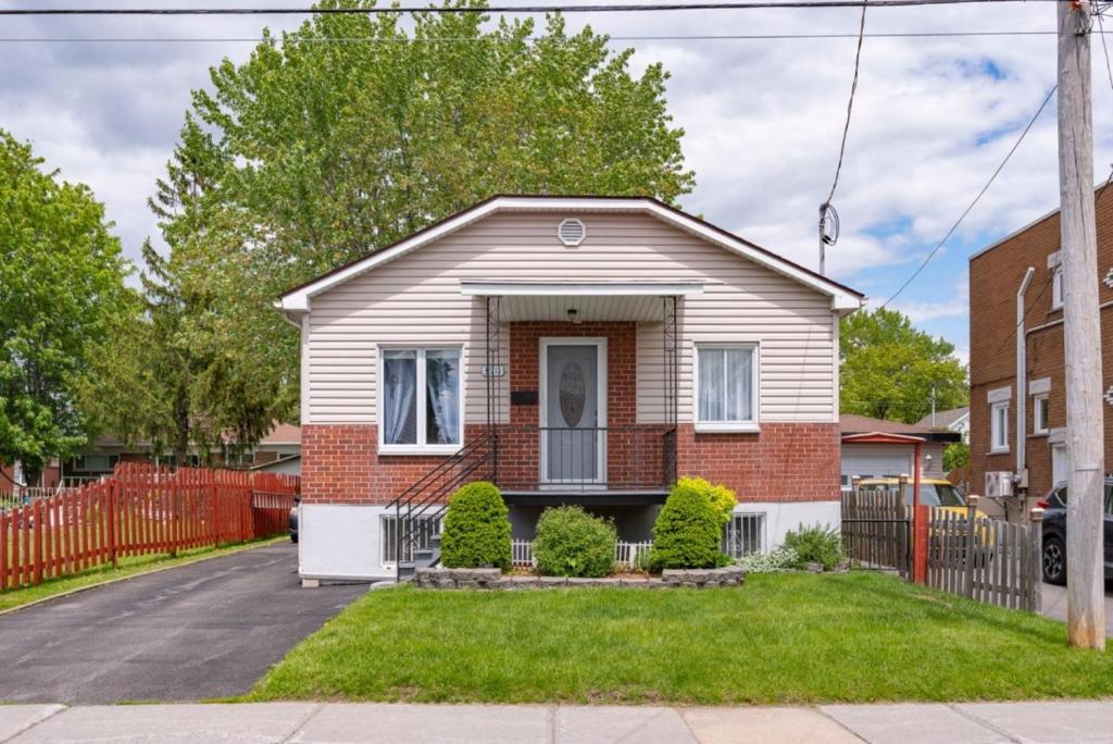 a white and red house with a fence at Le Milka II in Longueuil