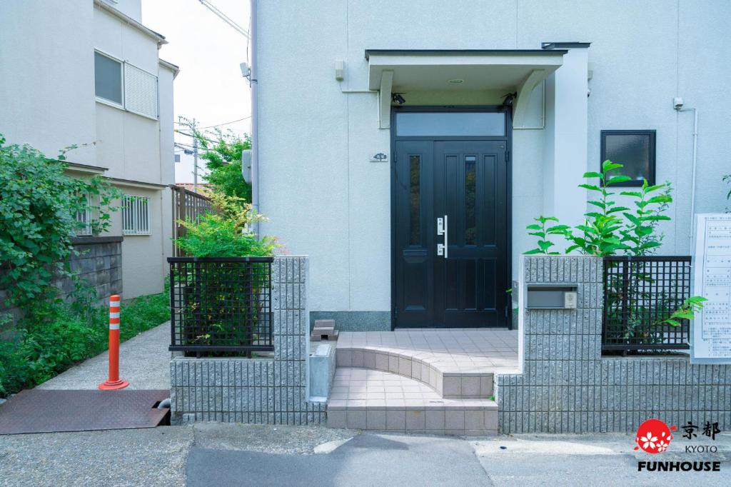 a black door on a white building with stairs at Funhouse Kaori in Kami-tobachō