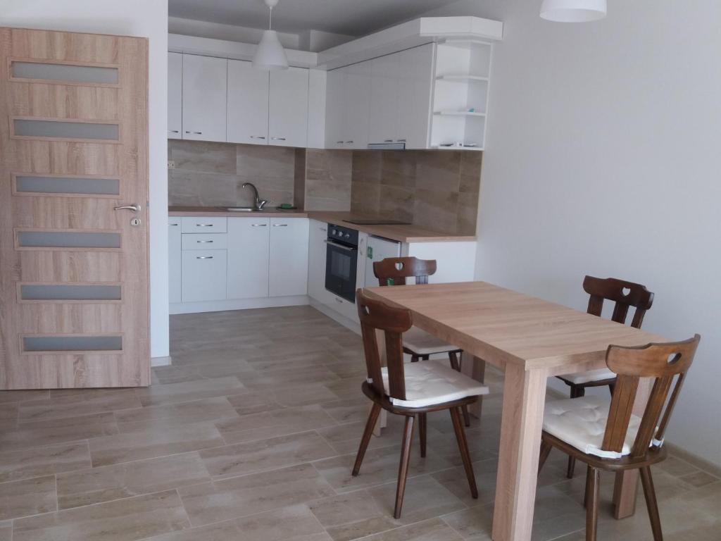 una cocina con armarios blancos y una mesa y sillas de madera. en Лукс апартамент Алекс en Blagoevgrado