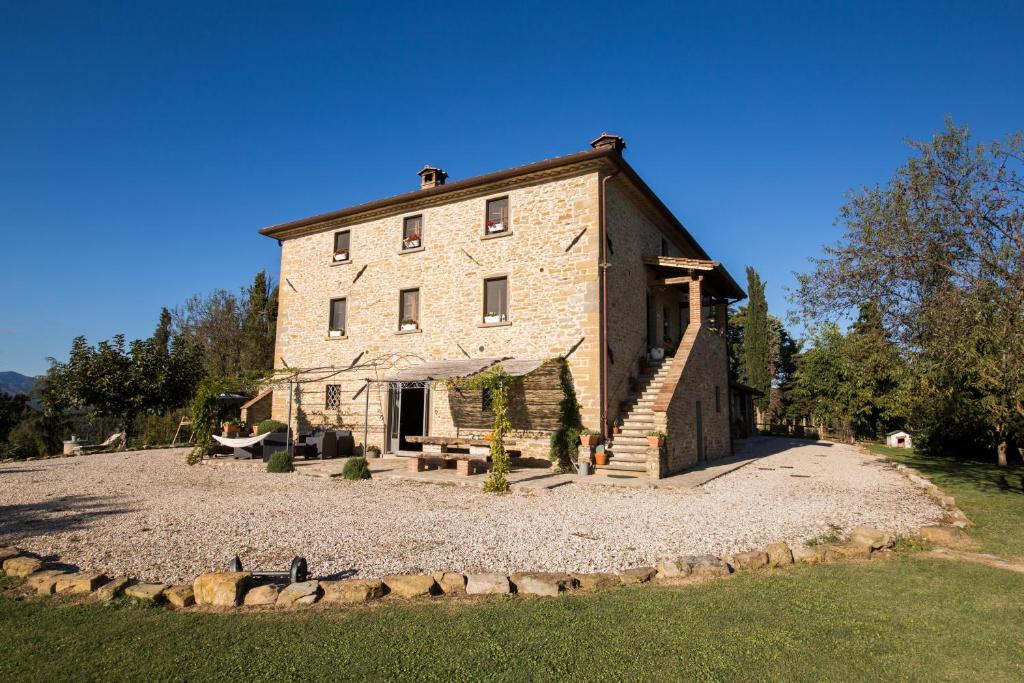 un grande edificio in pietra su una collina con un prato di Le Terre di Caprano a Città di Castello