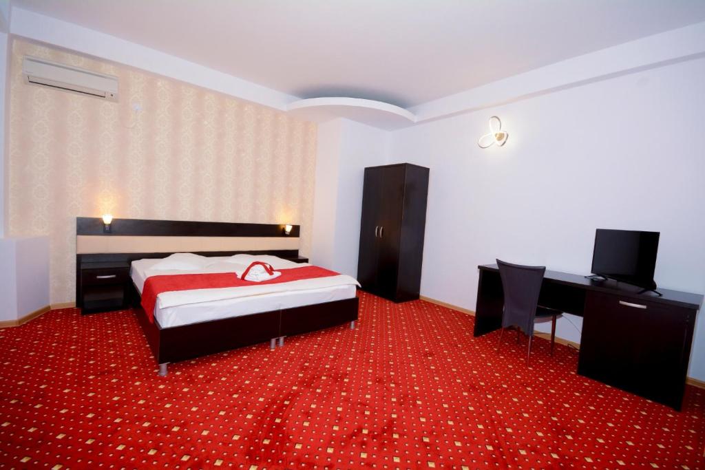 una camera con letto e tappeto rosso di Hotel Magic - City Center a Piteşti