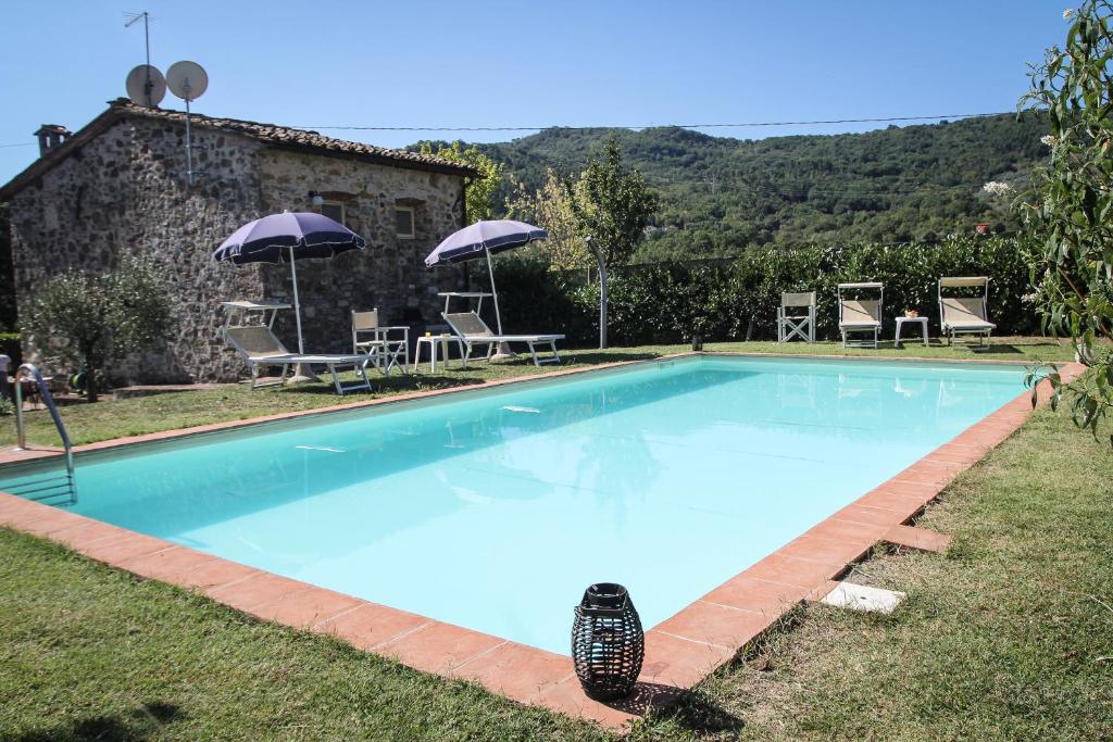 una gran piscina azul con sillas y sombrillas en Casa Patrizia, en Borgo a Mozzano