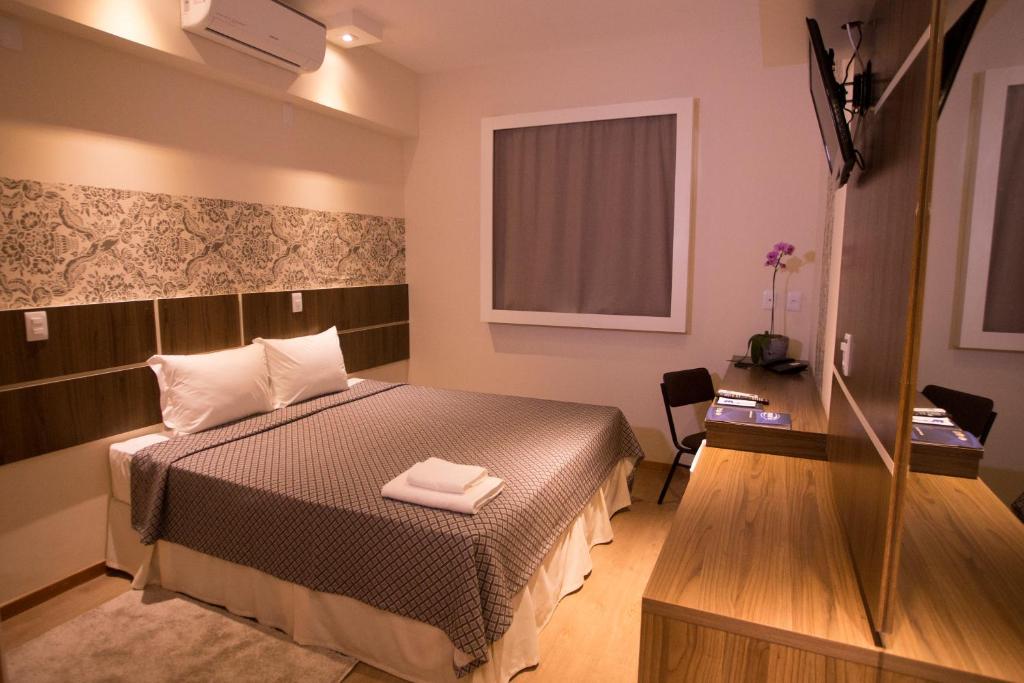 Habitación pequeña con cama y escritorio. en Druds Hotel Hortolândia, en Hortolândia