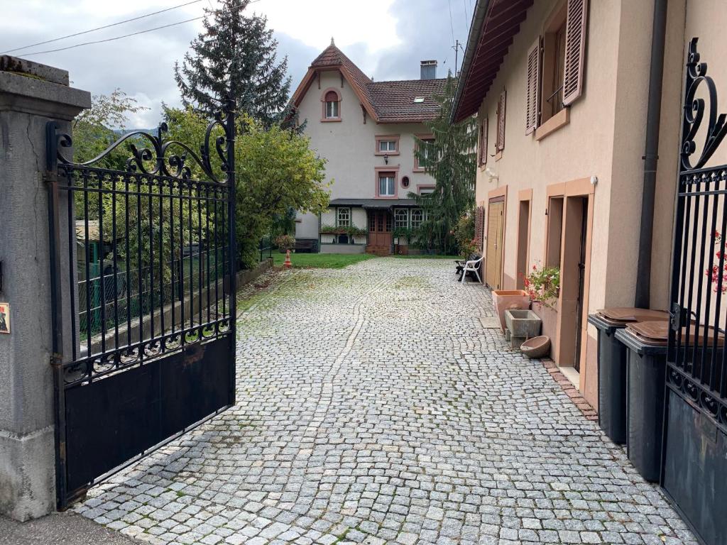 a cobblestone street with a gate in front of a house at Chambre Gentiane 2 à 3 personnes wifi sdb partagée in Saint-Amarin