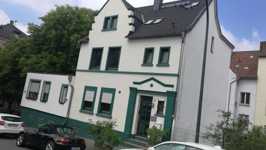 a white and green house with a car parked in front at Pension Hoffmann in Wuppertal
