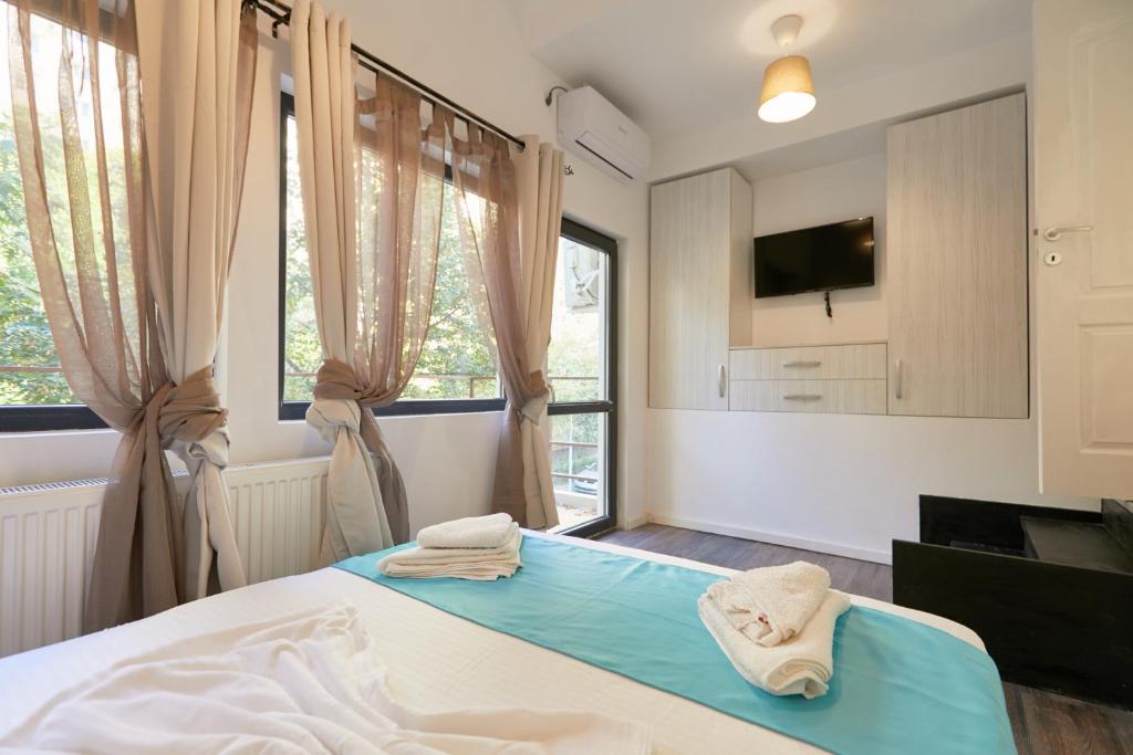 a bedroom with a bed and a tv and windows at Stanford apartments in Bucharest