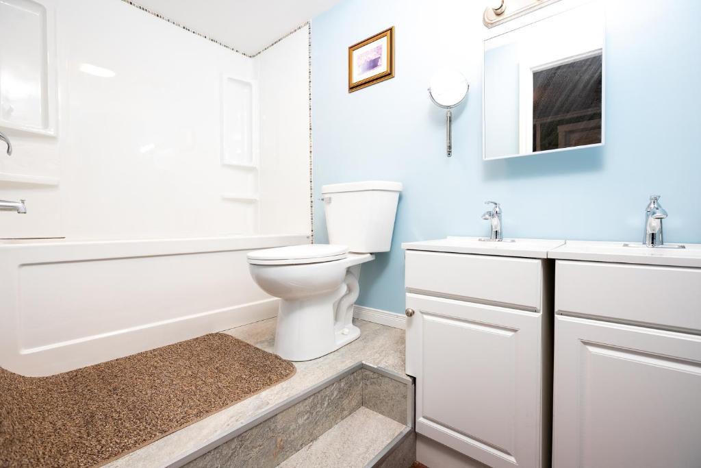 a bathroom with a white toilet and a tub and a sink at Lily's garden in Charlottetown