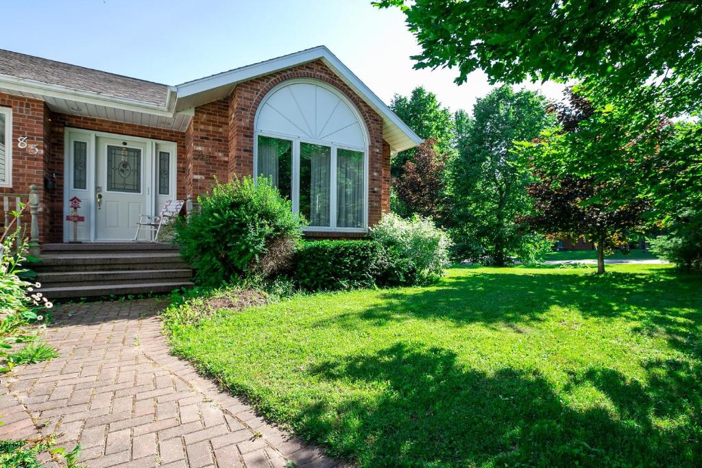 a brick house with a porch and a lawn at Lily's garden in Charlottetown