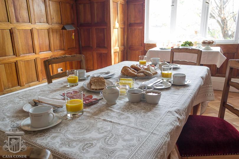 a table with a breakfast of bread and orange juice at Hotel Boutique Casa Conde in Santiago