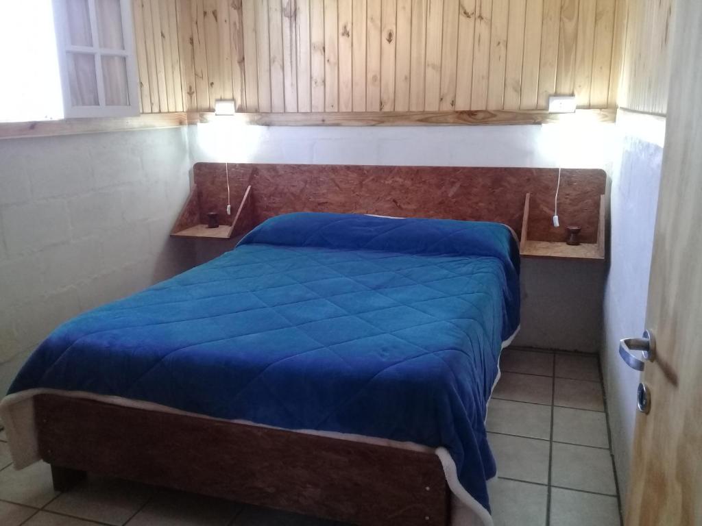 ein Schlafzimmer mit einem Bett mit einer blauen Decke darauf in der Unterkunft LA PALMERA in Lunlunta