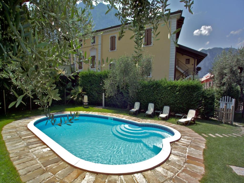 a swimming pool in a yard with chairs and a house at Residence Villa degli Aranci in Riva del Garda