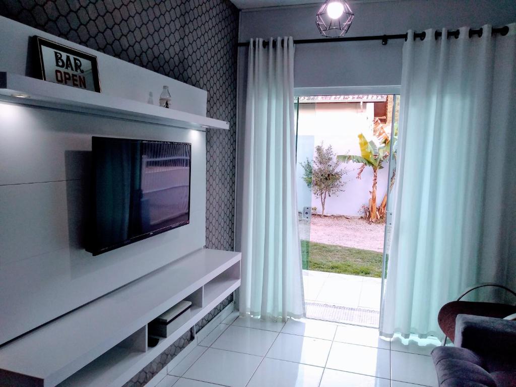 sala de estar con TV y puerta corredera de cristal en Casa aconchegante Joaquina, en Florianópolis