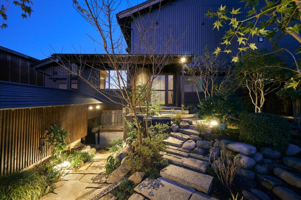 a garden with a stone path leading to a house with lights at Bed and Craft TenNE in Inami
