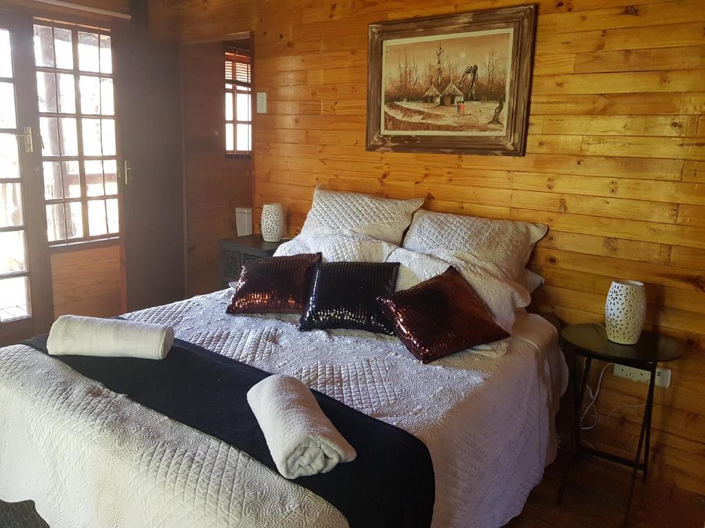 een slaapkamer met een bed met kussens erop bij Cozy Wood Cabin in Pretoria