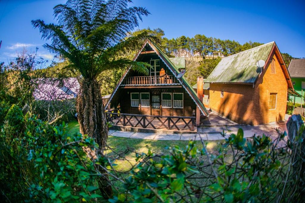 a house with a tree in front of it at Chalé do Vale Encantado in Campos do Jordão