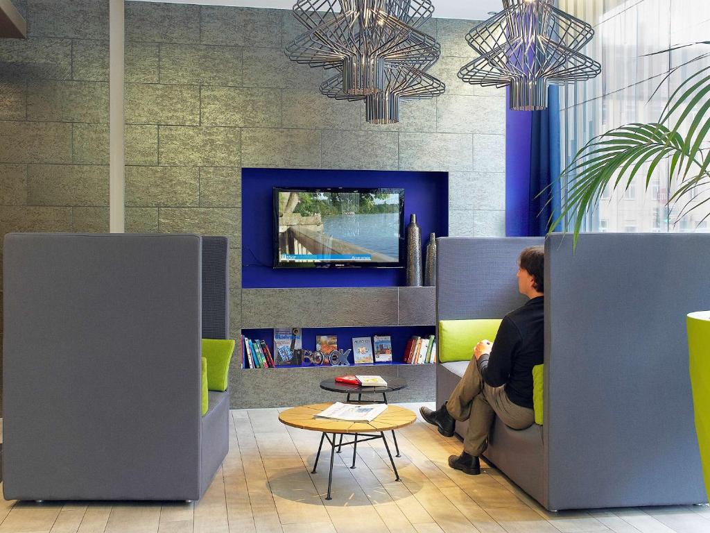 a man sitting on a couch in a room with a tv at Aparthotel Adagio Muenchen City in Munich