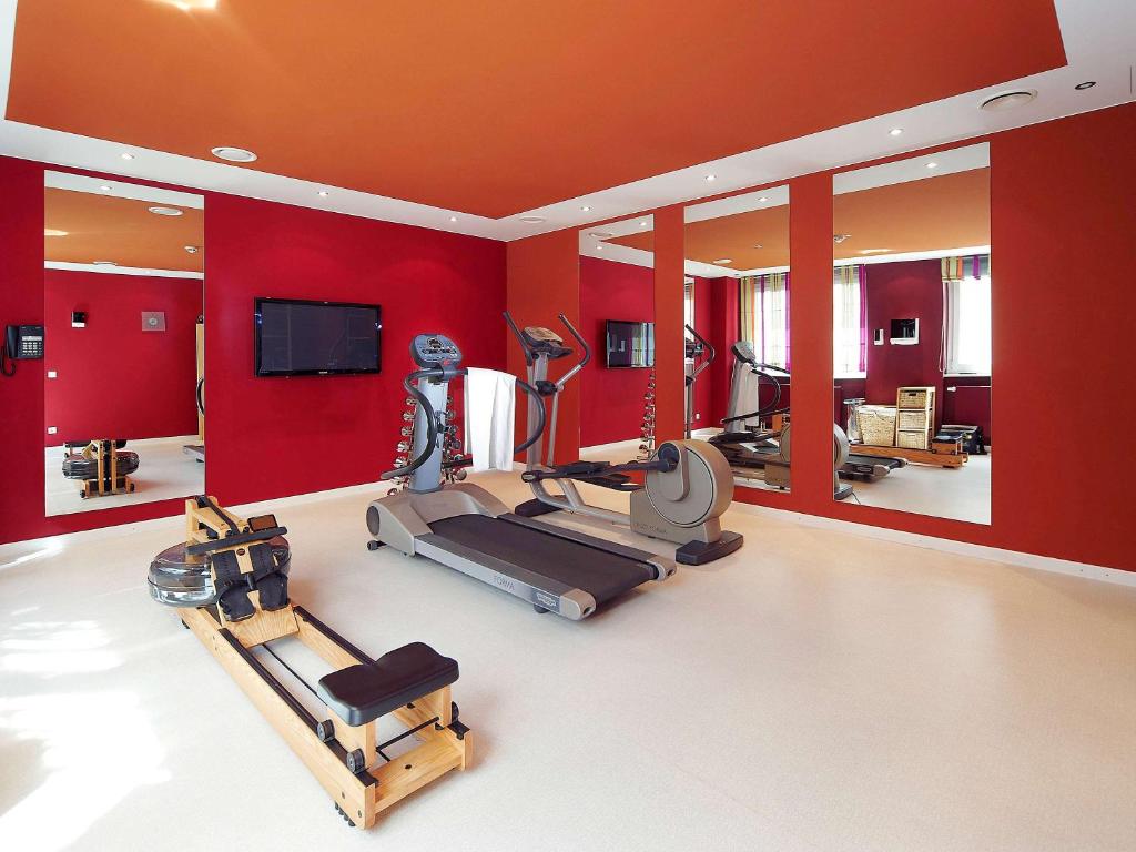 a gym with red walls and tread machines and a flat screen tv at Aparthotel Adagio Muenchen City in Munich