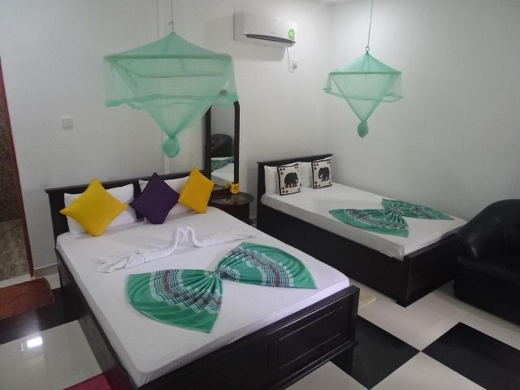 Habitación con 2 camas y espejo. en Sigiriya Camellia Home Stay, en Sigiriya