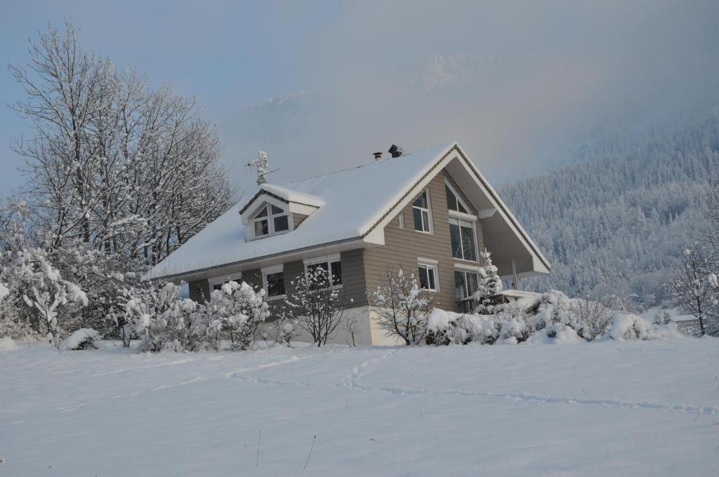 a house with a snow covered roof in a field at le montanet in Thollon