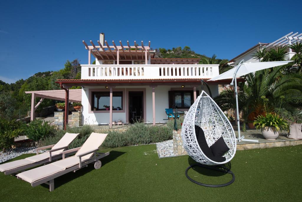 a house with a garden with chairs and an umbrella at Agnantema Villas in Aghios Petros Alonissos