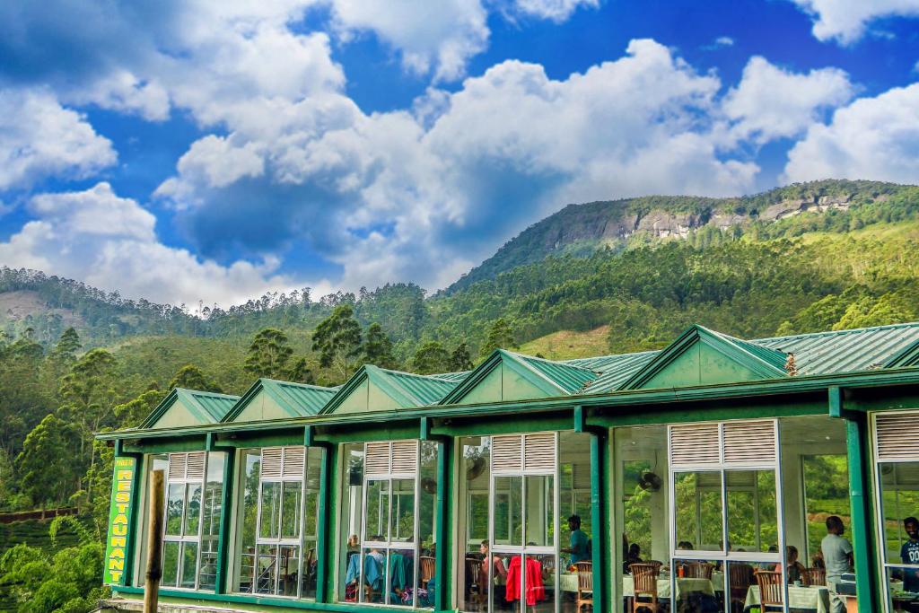 um edifício com janelas e montanhas ao fundo em Punsisi Resort - Adam's Peak em Nallathanniya