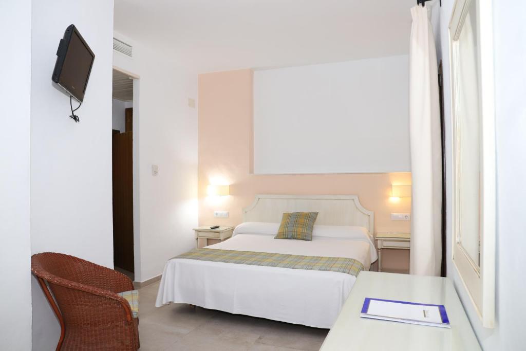 um quarto com uma cama, uma mesa e uma televisão em Hostal Doña Lola Marina em Zahara de los Atunes