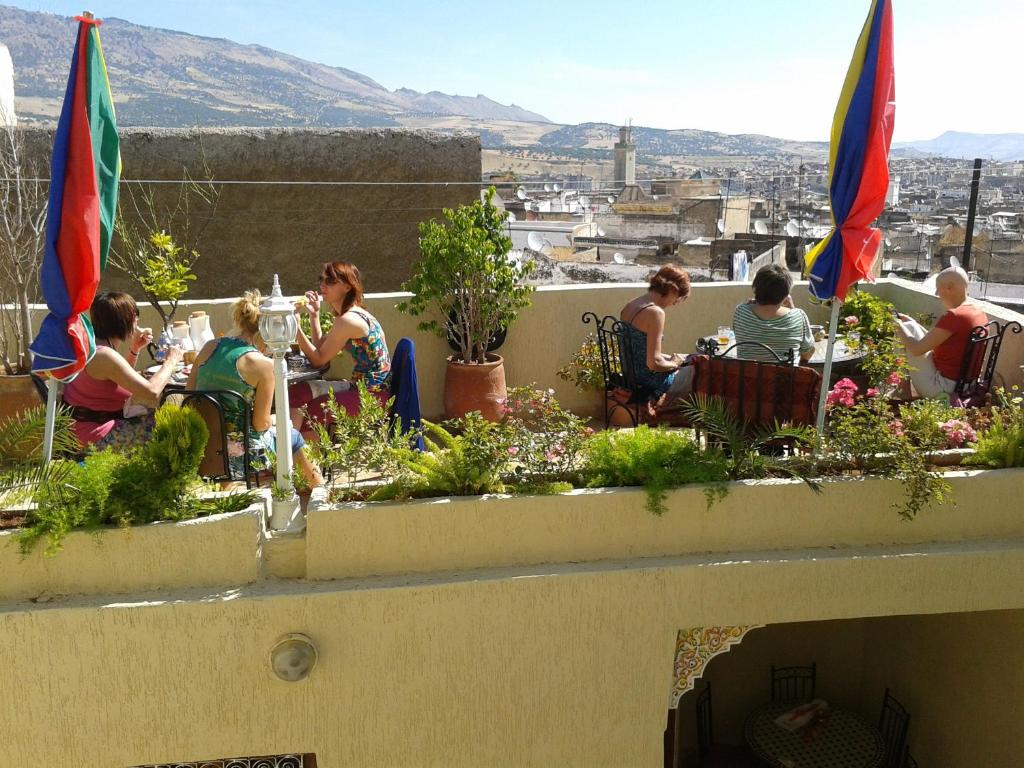 un groupe de personnes assises à des tables sur un toit dans l'établissement Maison Famille Tazi, à Fès