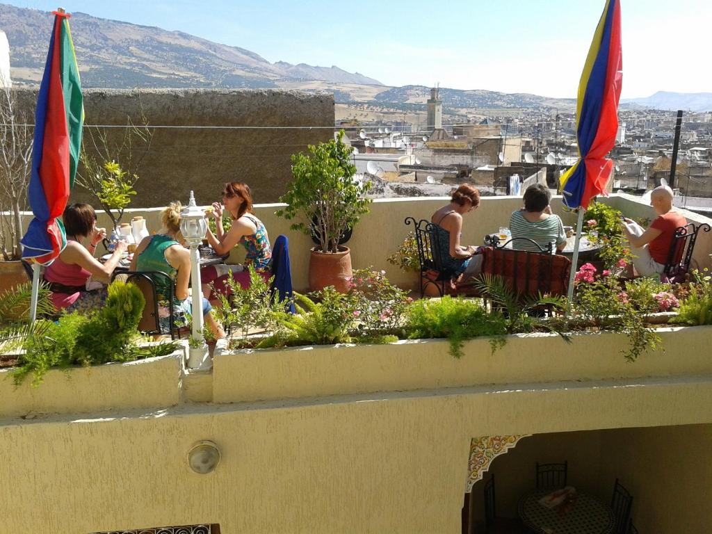 a group of people sitting at tables on a roof at Maison Famille Tazi in Fès