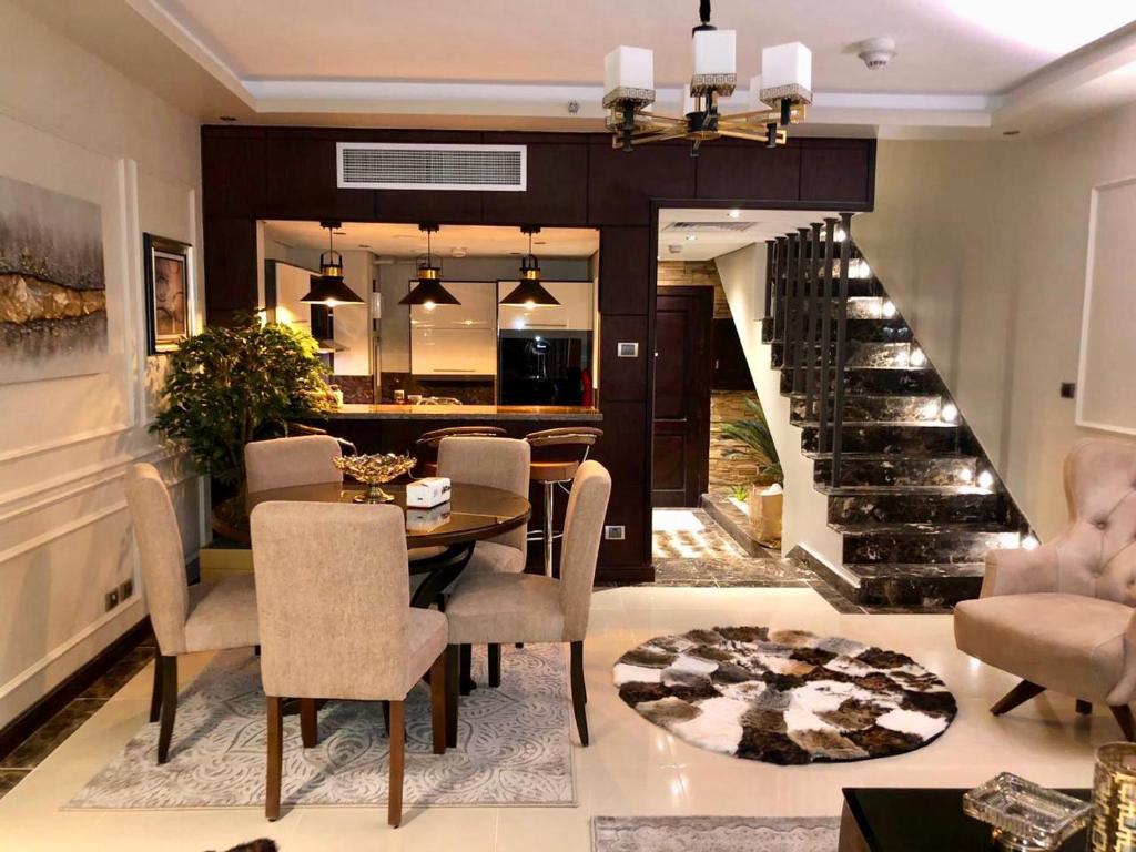 a dining room with a table and chairs and a staircase at دوبلوكس نيو بورتو كايرو القاهرة الجديدة للعائلات فقط in Cairo