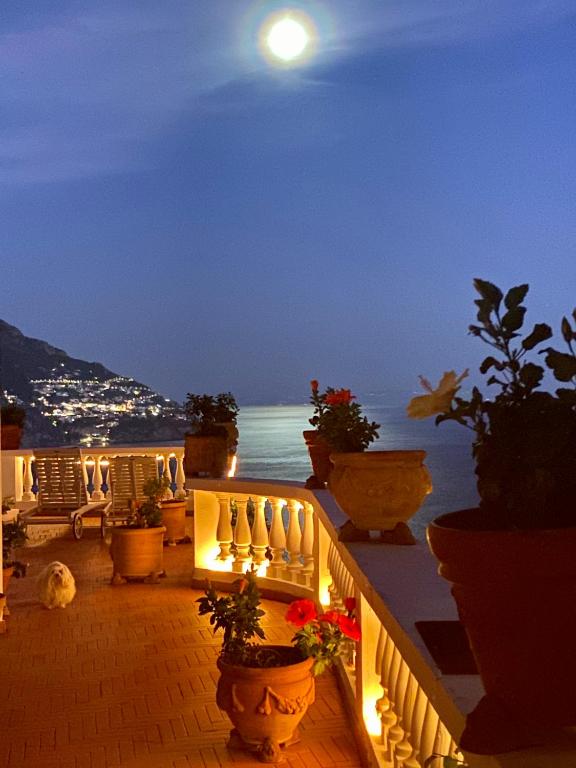 a balcony with potted plants and the ocean at night at Villa Briganti Seaview Terrace in Positano