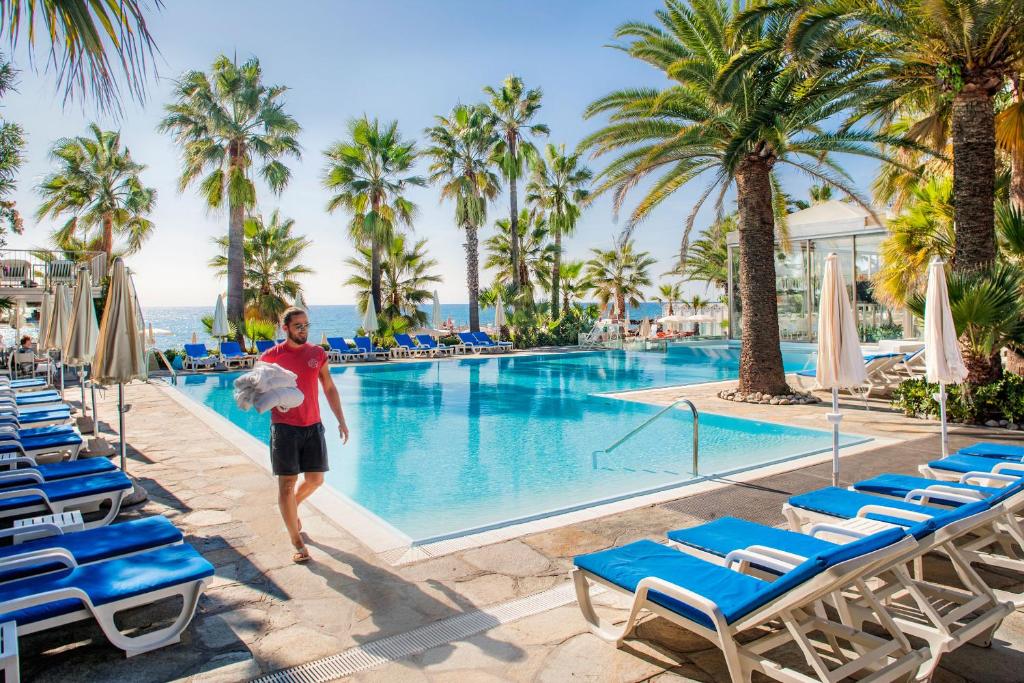 una donna in piedi di fronte alla piscina di un resort di Hotel Caravelle Thalasso & Wellness a Diano Marina