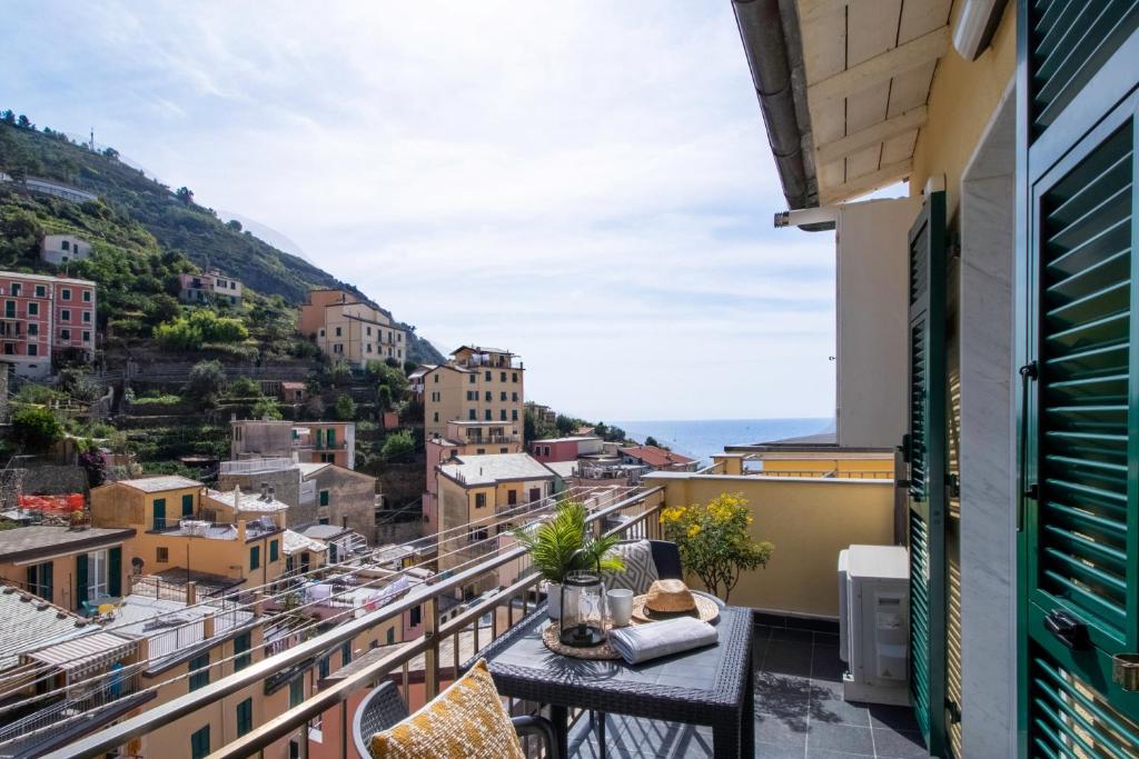 a balcony with a table and chairs looking out at the city at Zagara apartment in Riomaggiore