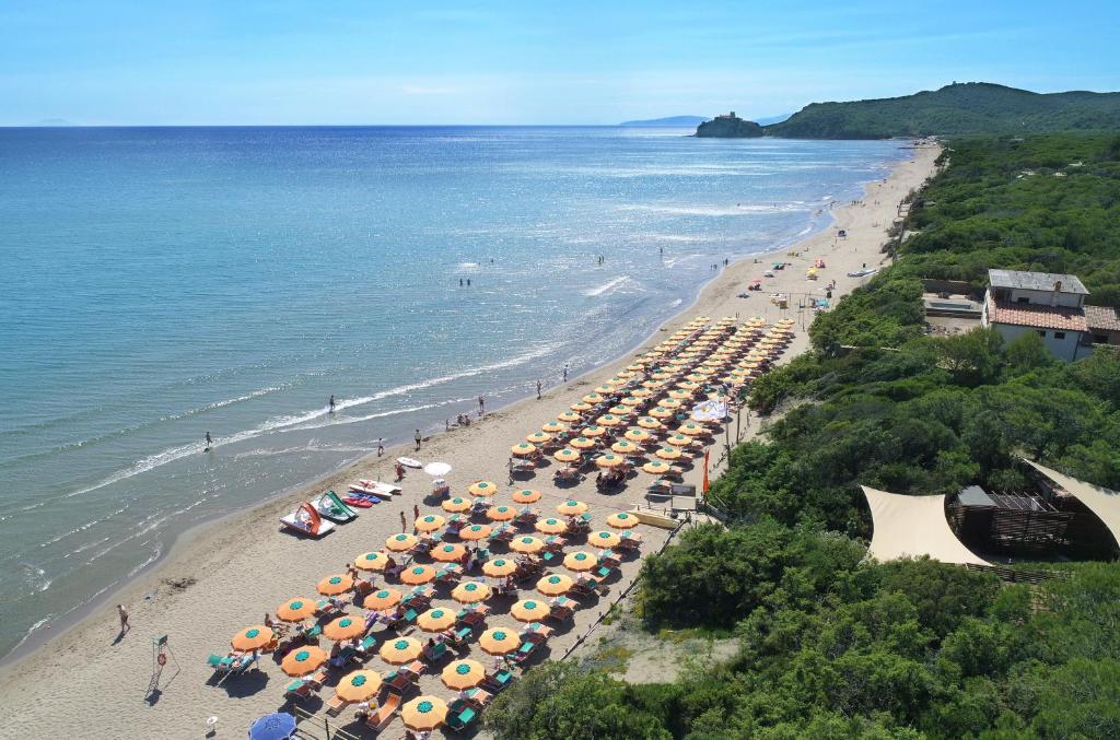 een uitzicht over een strand met veel parasols bij Camping Village Santapomata in Castiglione della Pescaia