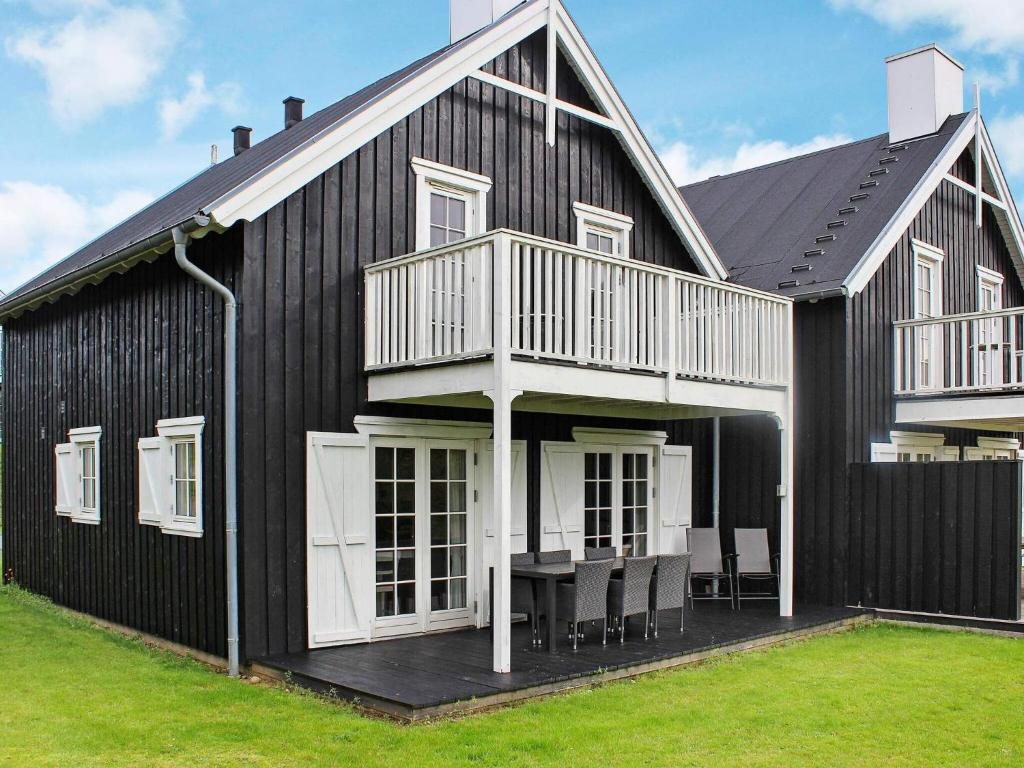 uma casa preta com um deque, uma mesa e cadeiras em 4 star holiday home in Gjern em Gjern