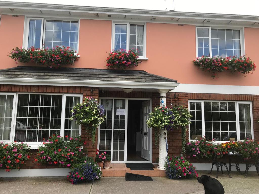 une maison rose avec des boîtes de fleurs sur les fenêtres dans l'établissement Cillcearn House, à Killarney