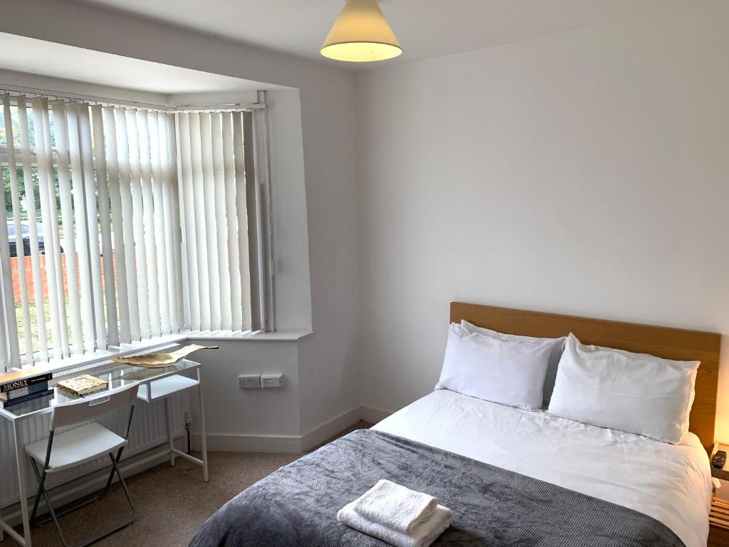 Schlafzimmer mit einem Bett, einem Schreibtisch und Fenstern in der Unterkunft The great airport place-private bedrooms with private bathroom-1 Bus to Heathrow Airport-5 minutes by car- Helpful advice from our team in Harmondsworth