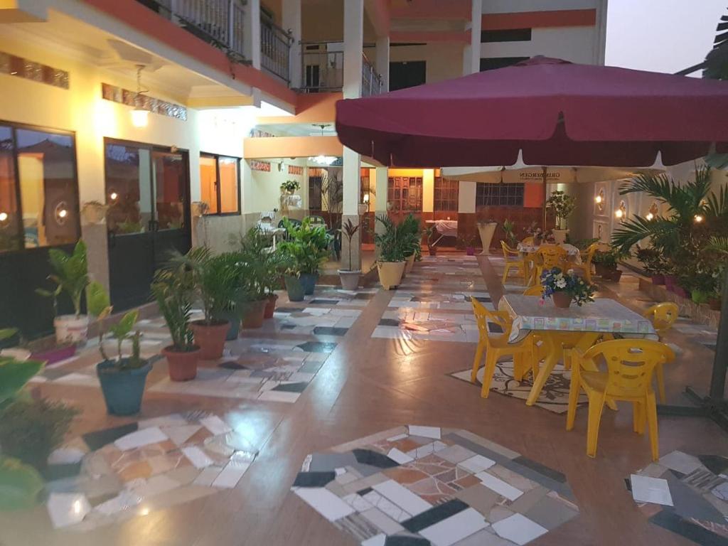 um restaurante com mesas e cadeiras e um guarda-sol roxo em Afilux Residencial em Luanda