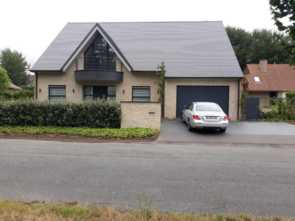 ein Auto, das vor einem Haus mit Garage parkt in der Unterkunft Luxueus duplex appartement aan zee in Koksijde