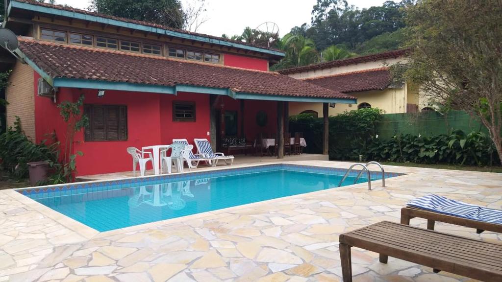 een zwembad voor een rood huis bij Linda casa Boicucanga in São Sebastião