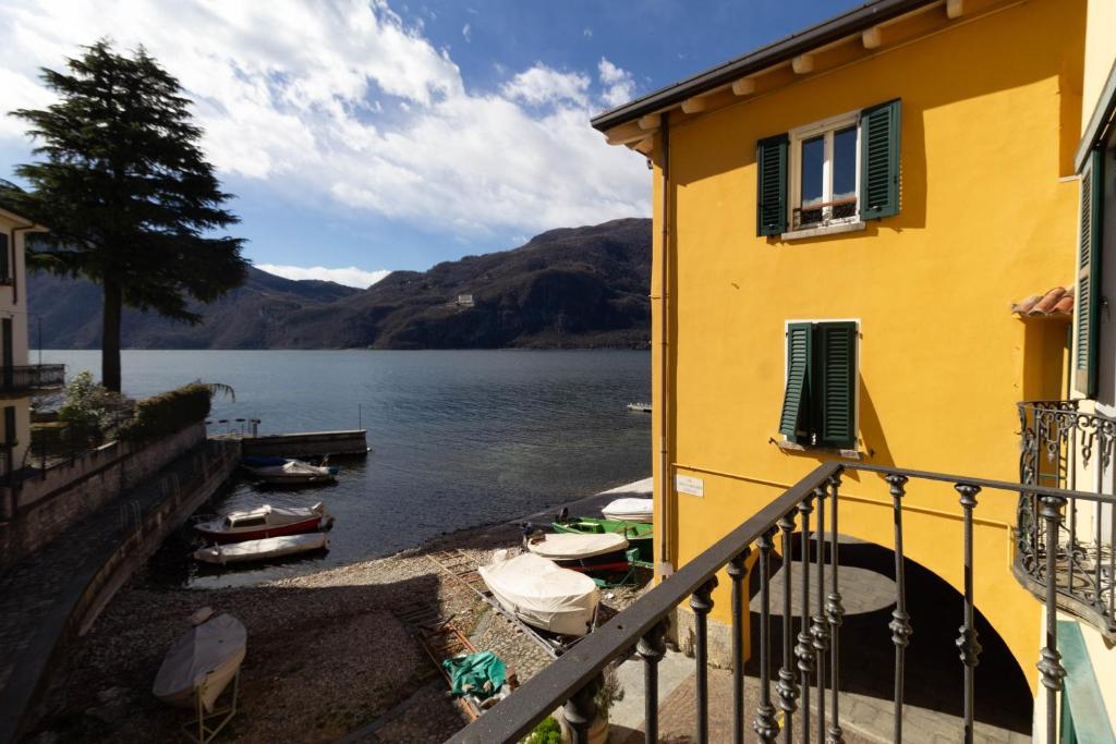 a yellow building next to a body of water with boats at Mamma Ciccia Holiday Home - Lake Front Apartment in Mandello del Lario