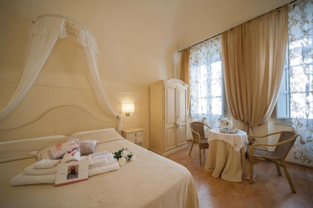 ein Schlafzimmer mit einem weißen Bett mit Blumen und einem Tisch in der Unterkunft Albergo Etruria in Volterra