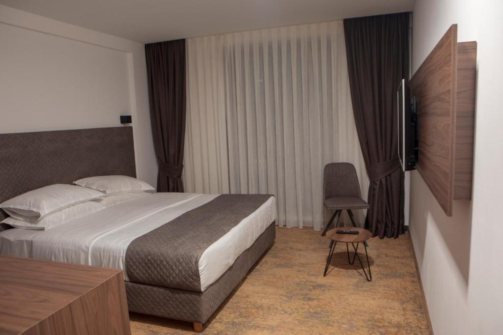 a hotel room with a bed and a chair at Qama Hotel in Prishtinë