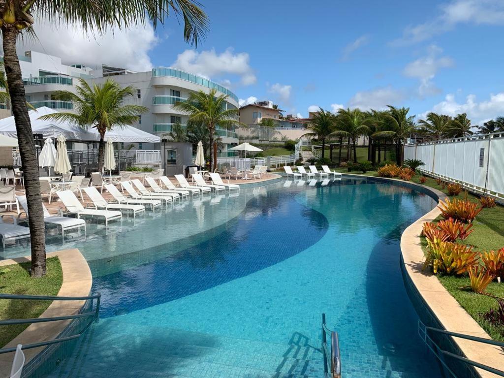 uma grande piscina com cadeiras brancas e palmeiras em In Mare Bali - Ala Muriu 332 em Granja Beira Mar