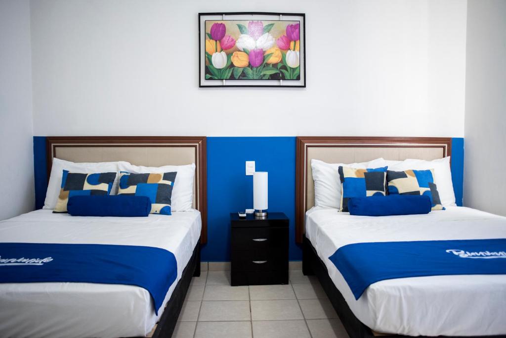 two beds in a room with blue walls at La Estancia Apartments Mazatlan in Mazatlán