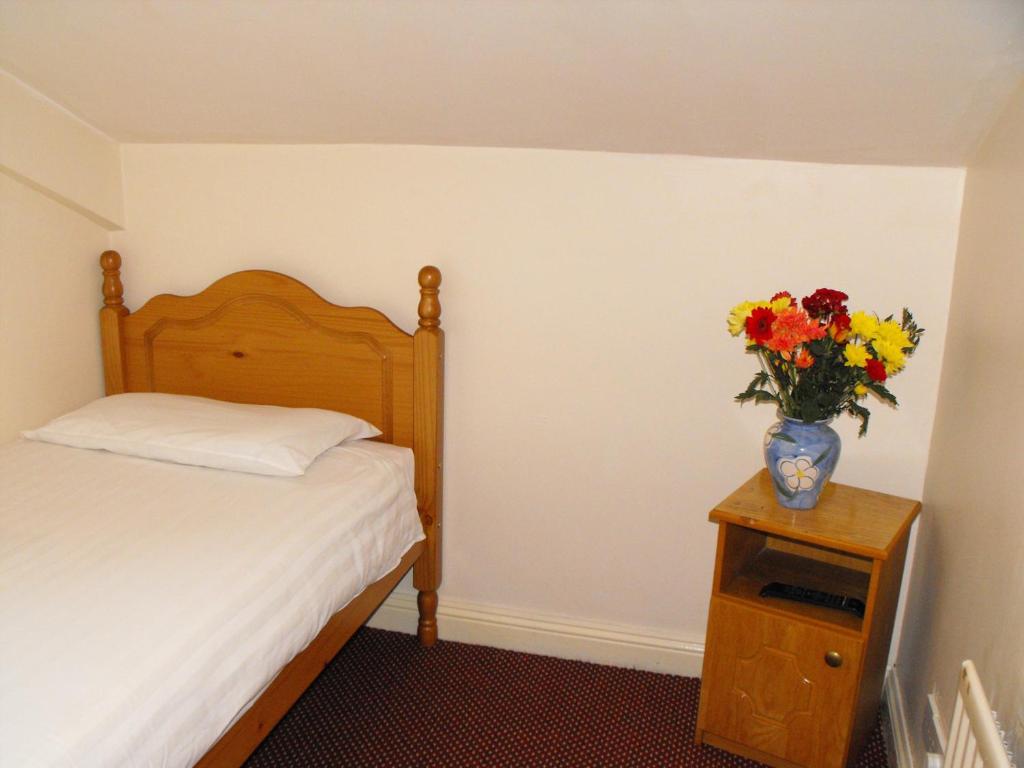 um quarto com uma cama e um vaso de flores sobre uma mesa em Hazelbrook Lodge em Dublin