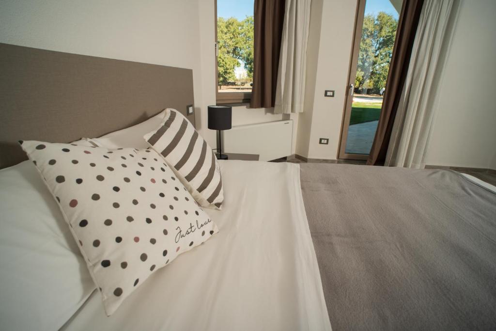 una camera da letto con un letto bianco con cuscini e una finestra di Regia Hotel ad Abbasanta