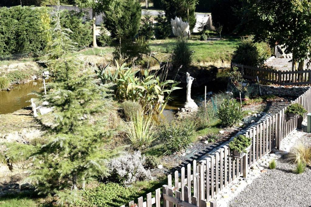 a wooden fence in a garden with a pond at La mare aux Canards, 8mn du Zoo de Beauval in Châteauvieux