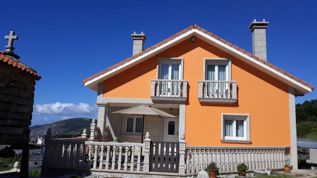 a orange house with a white fence at Mirador do faro Touriñan in Muxia