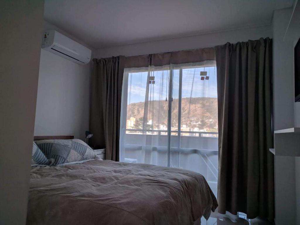 a bedroom with a bed and a large window at DEPARTAMENTO Edificio LEONARDO in Villa Carlos Paz